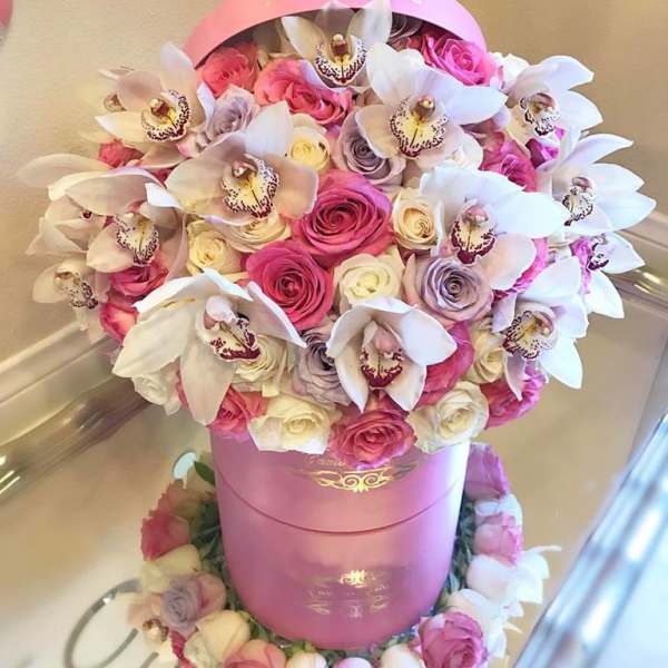 Pink and white roses with white orchids in a pink hatbox