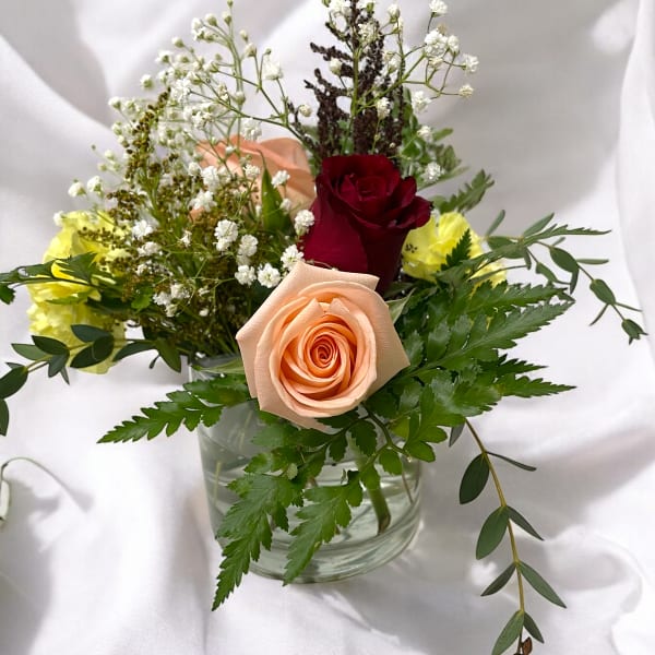 Mixed roses and filler flowers in a clear glass vase