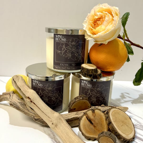 Three candles with an orange rose and citrus fruit accents