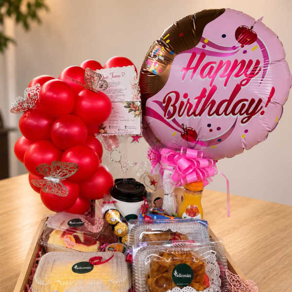 Birthday gift basket with red balloons, a pink birthday balloon, and packaged treats