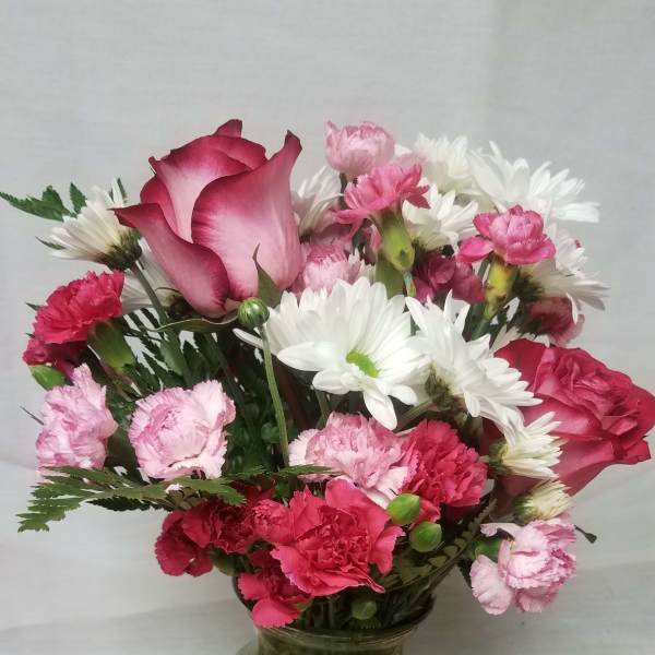 Pink roses, carnations, and white daisies in a glass vase