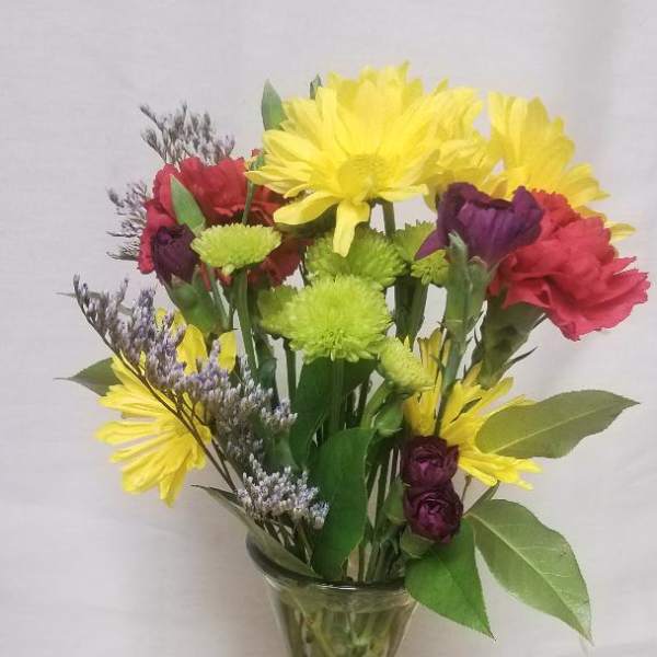 Mixed bouquet of yellow, red, and purple flowers in a clear glass vase