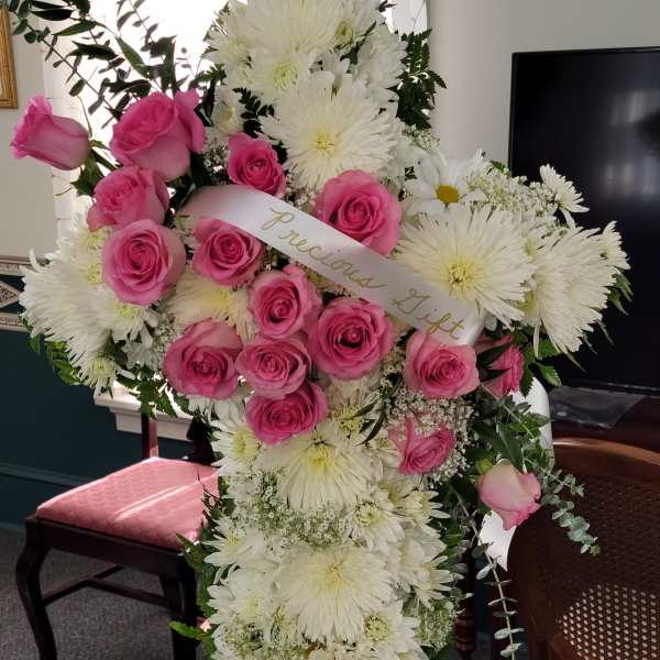 Pink roses and white chrysanthemums in a standing spray with a ribbon