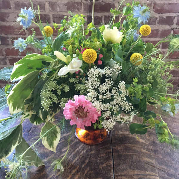 Mixed floral arrangement in a copper vase with blue, yellow, white, and pink blooms