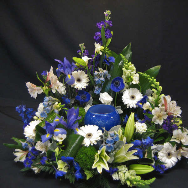 Blue and white floral arrangement with a blue glass candle holder in the center