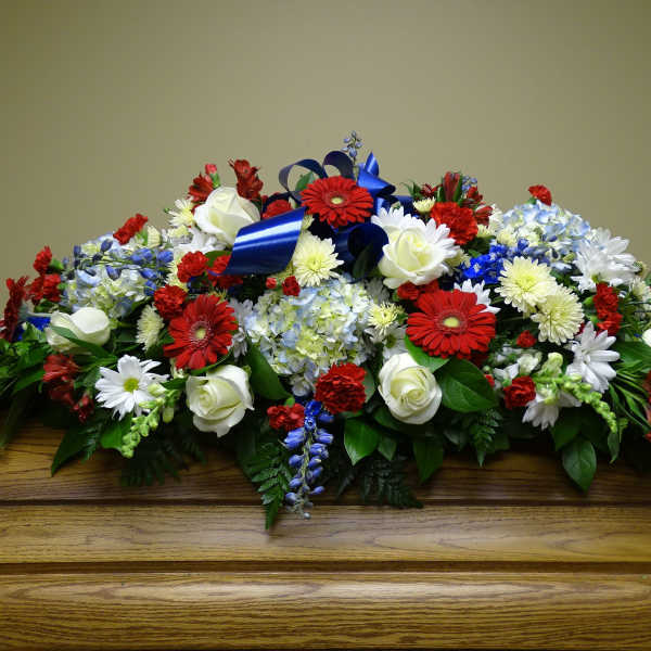 Large floral casket spray with red, white, and blue flowers