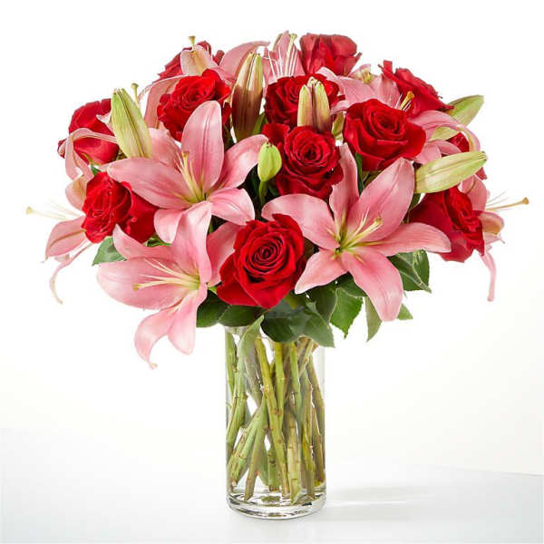 Bouquet of red roses and pink lilies in a clear glass vase