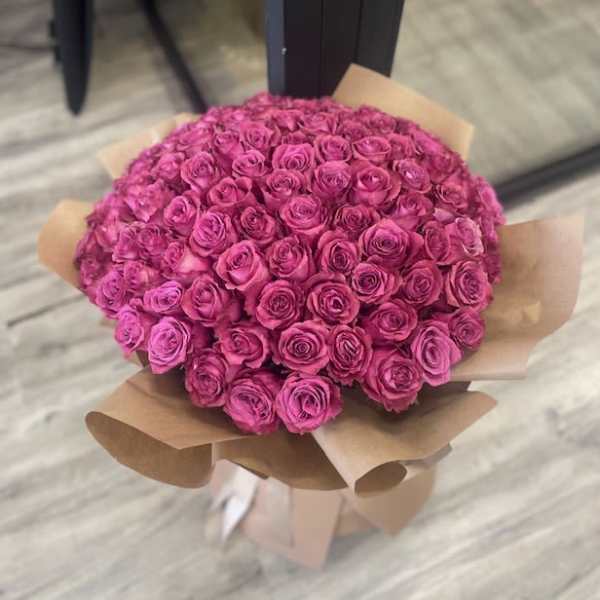 Large bouquet of pink roses wrapped in brown paper