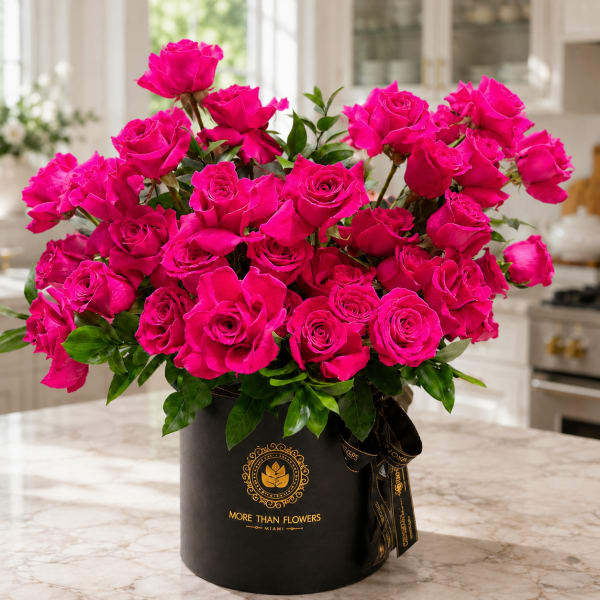 Hot pink roses arranged in a black hatbox with a ribbon
