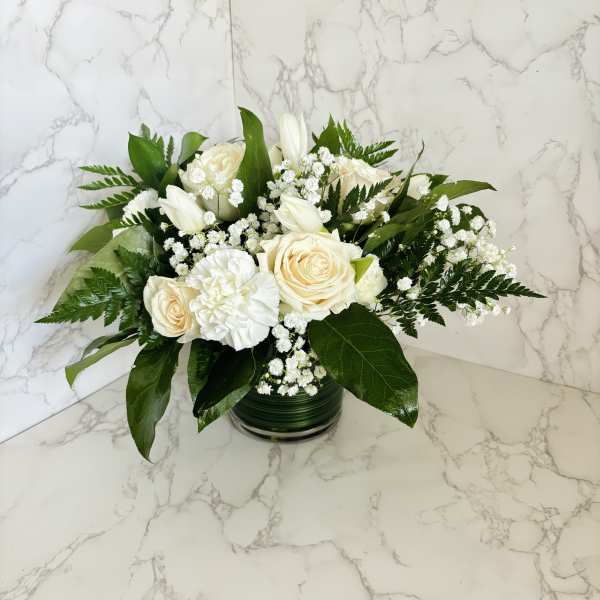 White roses and tulips arranged in a glass vase