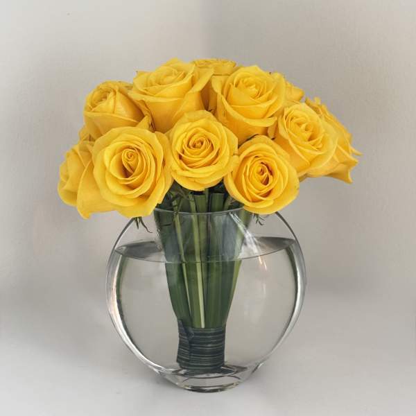 Yellow roses arranged in a clear round glass vase