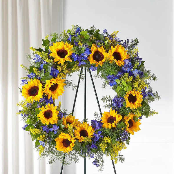 Sunflower wreath with blue flowers on a black stand
