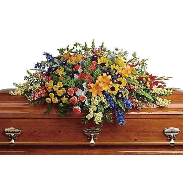 Colorful casket spray with mixed flowers on a wooden coffin