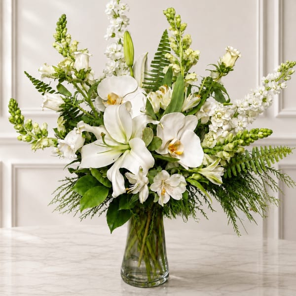 White orchids and lilies arranged in a clear glass vase
