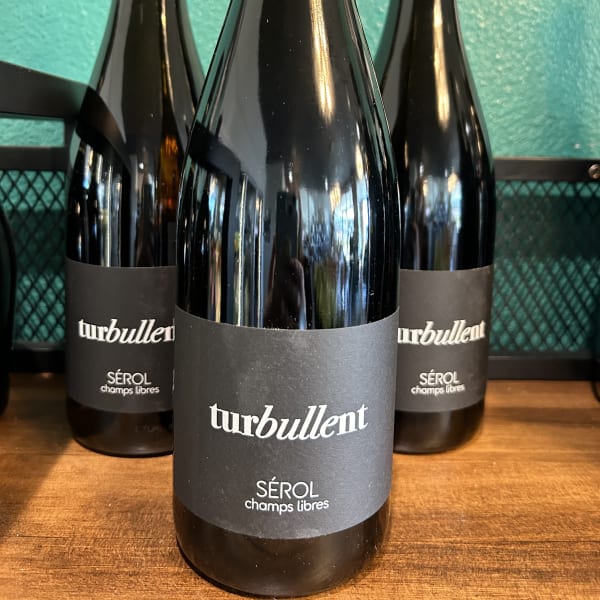 Three dark wine bottles with black labels on a wooden surface
