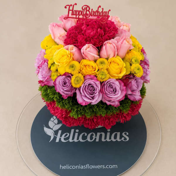 Round bouquet of pink, yellow, and lavender flowers with a Happy Birthday topper