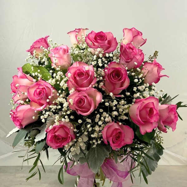 Pink roses arranged in a glass vase with baby's breath