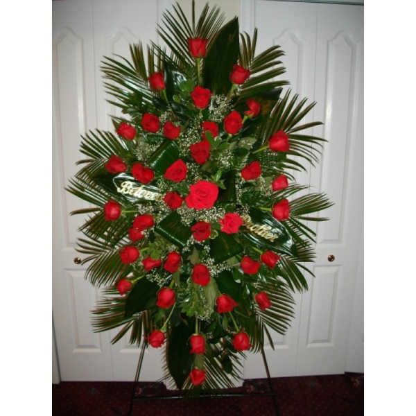 Standing spray of red roses with palm fronds on a metal easel