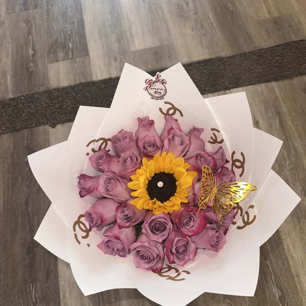 Bouquet of lavender roses with a yellow sunflower center in white wrap