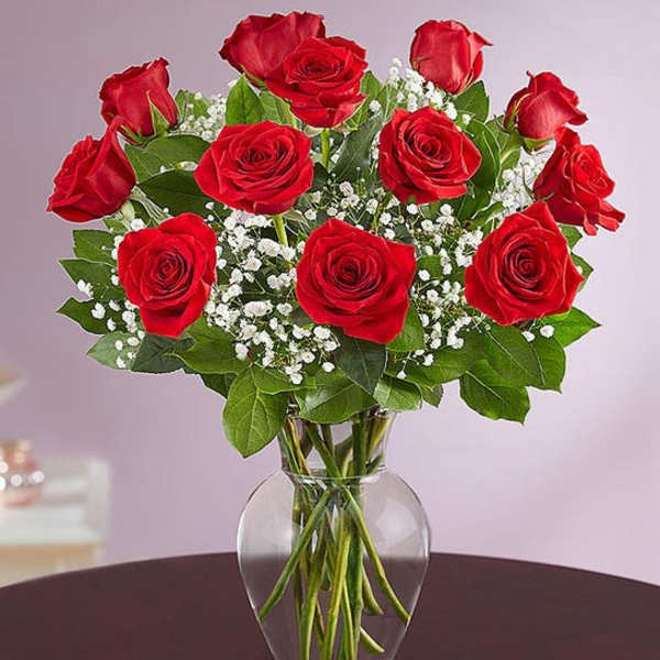 Red roses arranged in a clear glass vase with white baby's breath