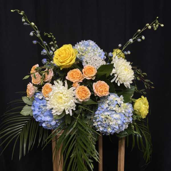 Mixed bouquet with yellow and peach roses, blue hydrangeas, and white chrysanthemums