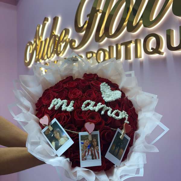 Heart-shaped bouquet of red roses with white wrapping and photo clips