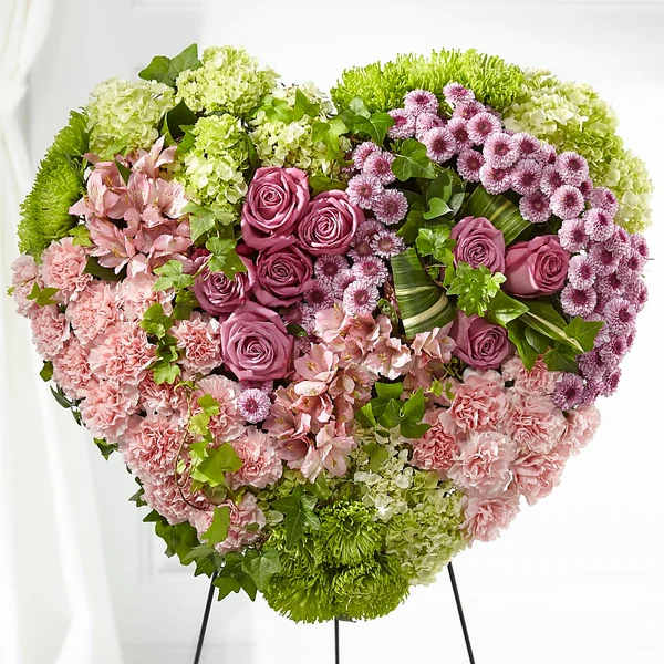Heart-shaped floral arrangement with pink roses, carnations, and green hydrangeas