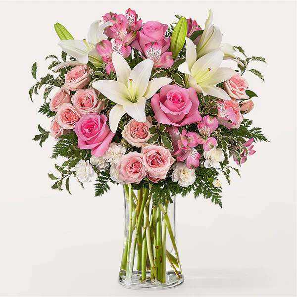 Pink roses and white lilies arranged in a clear glass vase