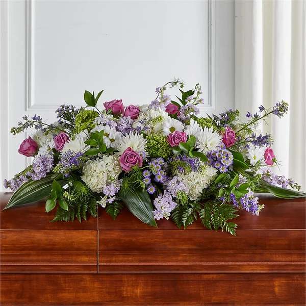 Low floral arrangement with pink roses, white blooms, and purple flowers