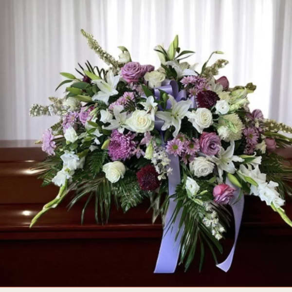 Large floral casket spray with white and lavender flowers and purple ribbon