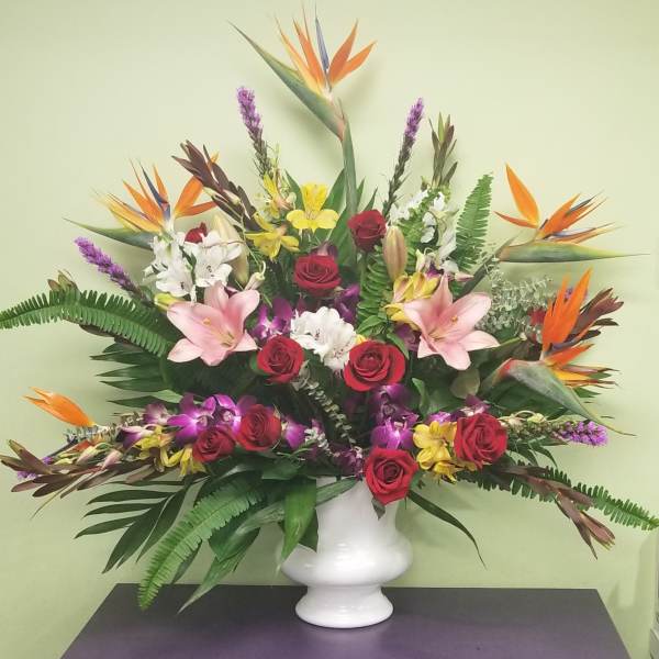 Tropical flower arrangement with roses, lilies, and bird-of-paradise in a white vase