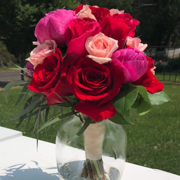 Bouquet of red, pink, and blush roses in a clear glass vase