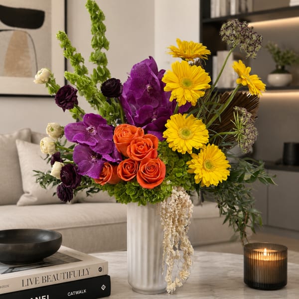 Bright mixed bouquet in a silver vase with purple, orange, and yellow flowers