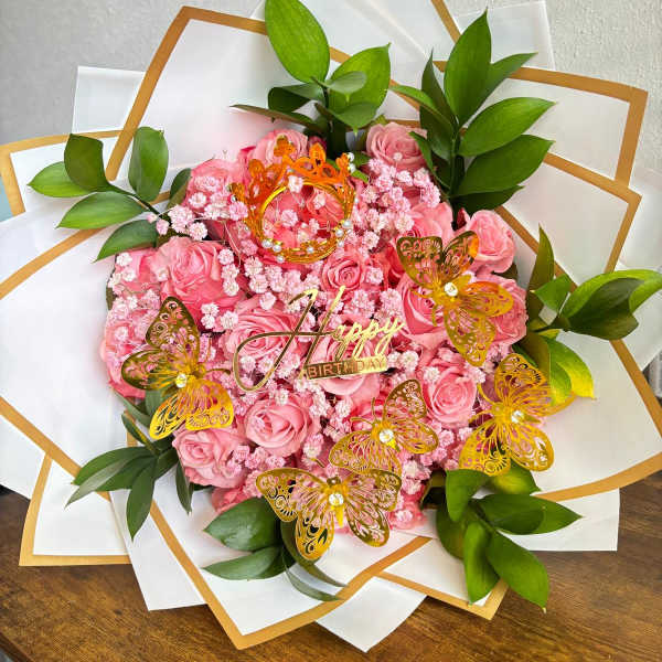 Pink rose bouquet with gold butterfly decorations and a Happy Birthday topper