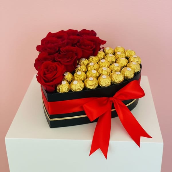 Heart-shaped box with red roses and gold-wrapped chocolates tied with a red ribbon