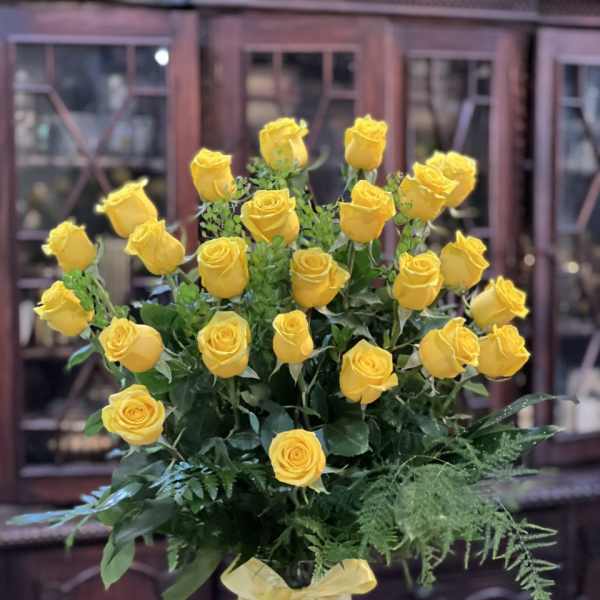 Yellow roses arranged in a clear glass vase with a ribbon