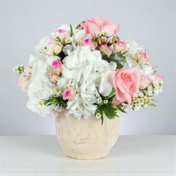 Pink and white rose bouquet in a cream vase