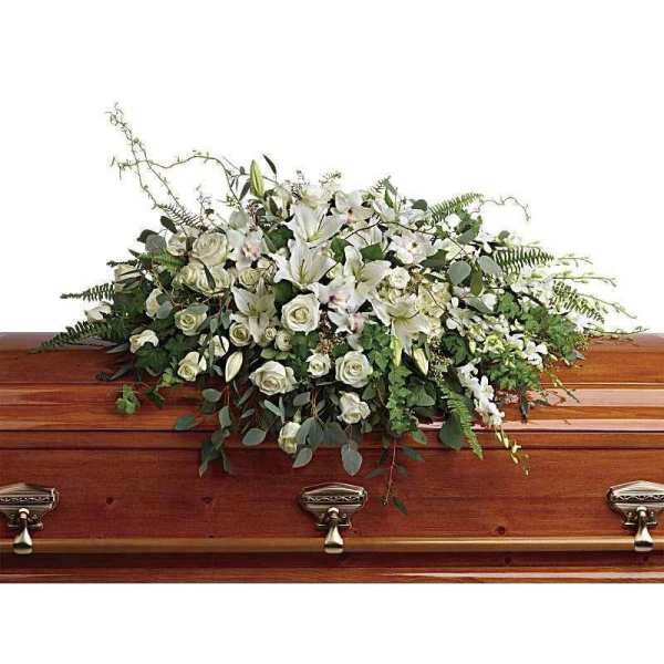 White floral casket spray on a wooden coffin