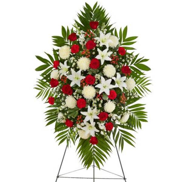 Standing spray of red roses, white lilies, and white mums with large palm fronds on an easel