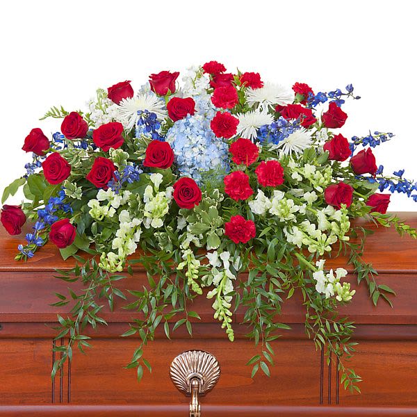 Red, white, and blue casket spray of mixed flowers on a wooden casket