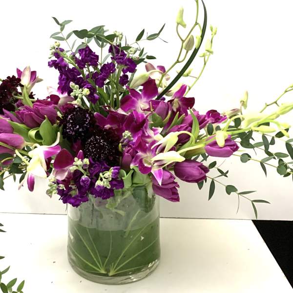 Purple tulips and orchids in a glass vase