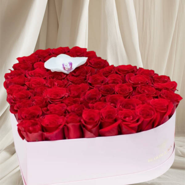 Heart-shaped box of red roses with a white orchid on top