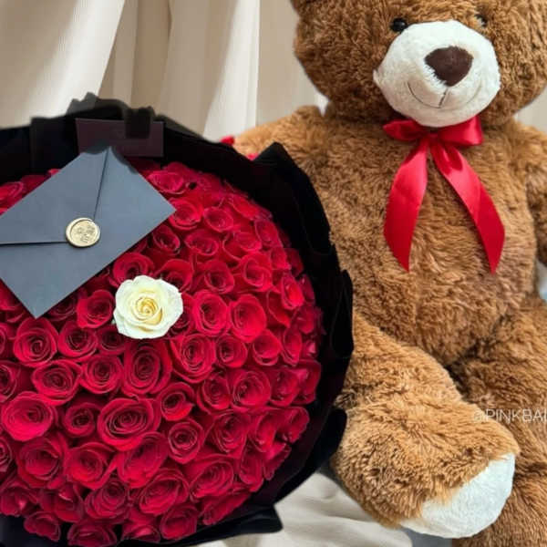 Bouquet of red roses with a white rose and a teddy bear