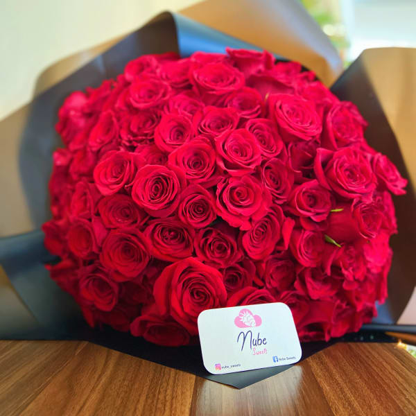 Large bouquet of red roses wrapped in dark paper