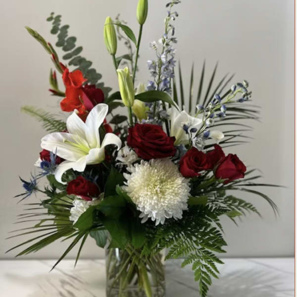 Mixed bouquet of red roses, white lilies, and white chrysanthemums in a glass vase