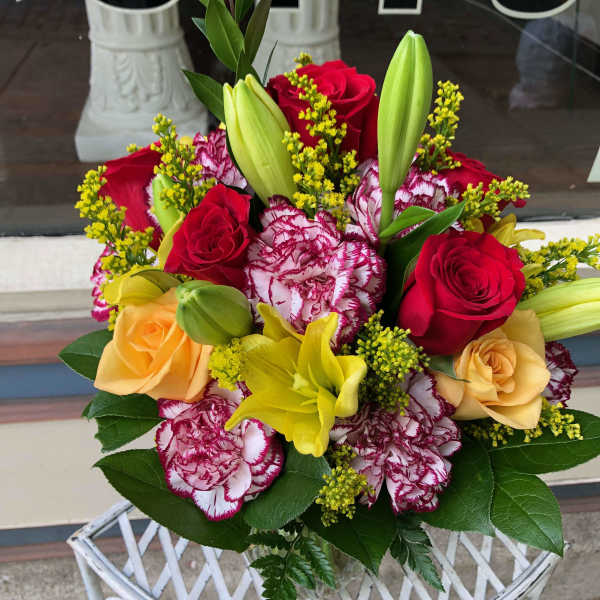 Bouquet of red and peach roses with yellow lilies and carnations