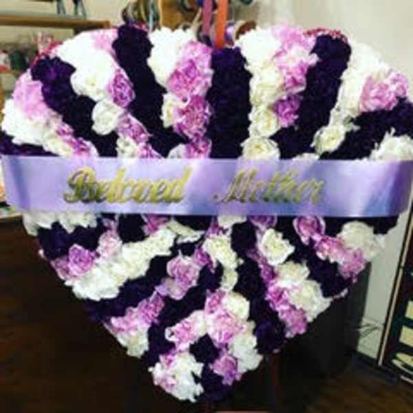 Heart-shaped floral tribute with pink, white, and dark purple flowers