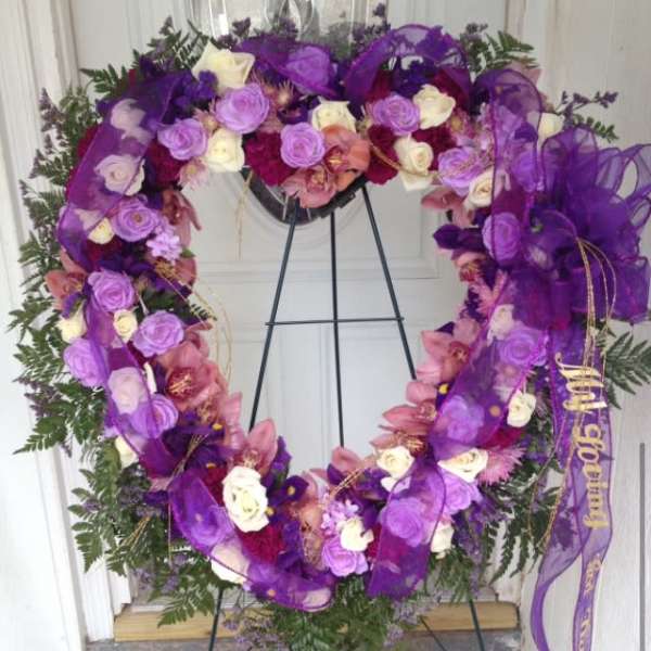 Purple floral wreath on a stand with roses and ribbon