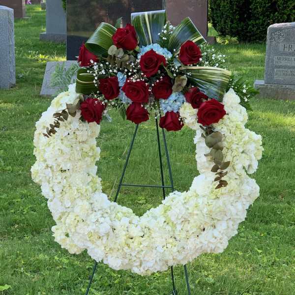Standing funeral wreath with white flowers and red roses on an easel