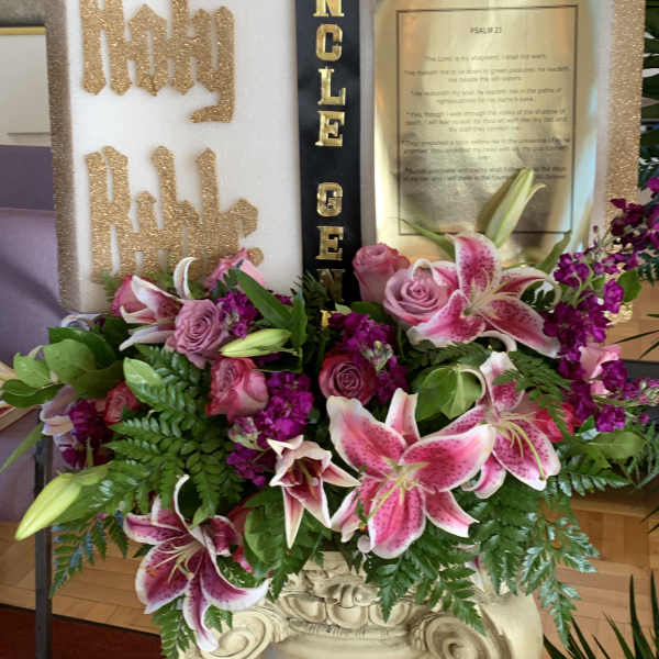 Pink lilies and roses arranged around a memorial display with gold lettering